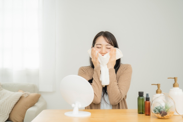スキンケア前にホットタオルを当てる女性