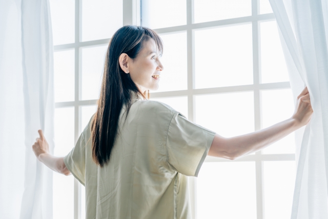 カーテンを開けている女性