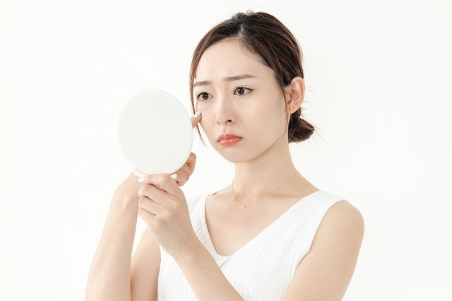 鏡を見て肌トラブルに困っている女性