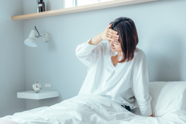 ベッドで辛そうな女性