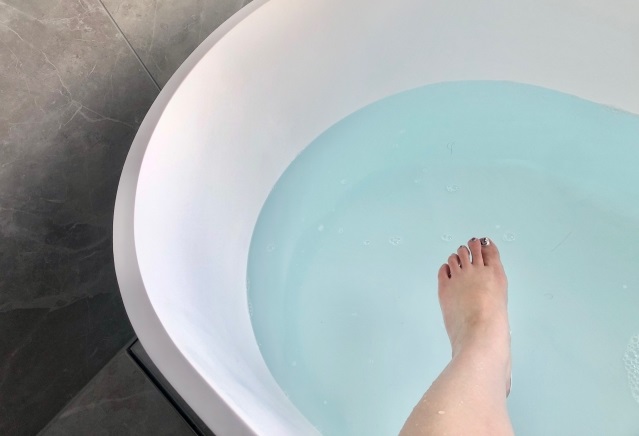 お風呂にためたお湯に足を入れようとする女性