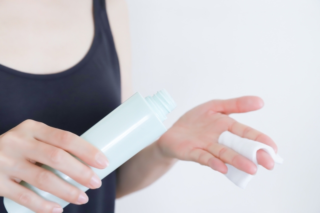 コットンを手に持ち、スキンケアの液をコットンにつける女性