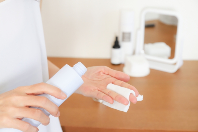 コットンに化粧水をしみ込ませようとしている女性