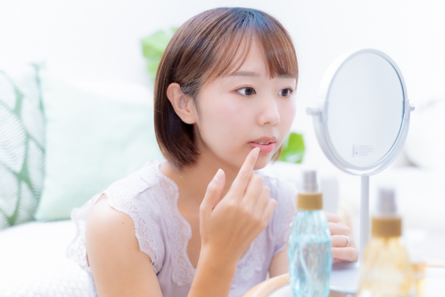 唇が荒れてしまい、鏡を見ながらケアする女性